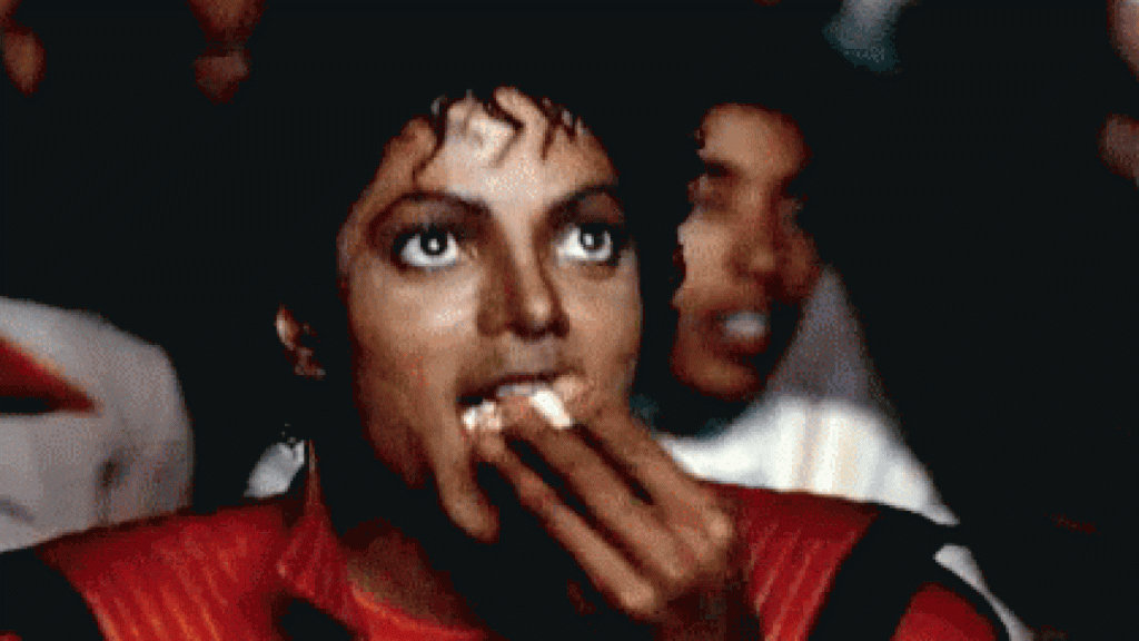 "Michael Jackson enjoying popcorn while captivated by something special, showcasing a moment of entertainment and delight."