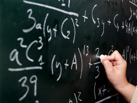 An image that shows a teacher writing on the blackboard explaining mathematical equations